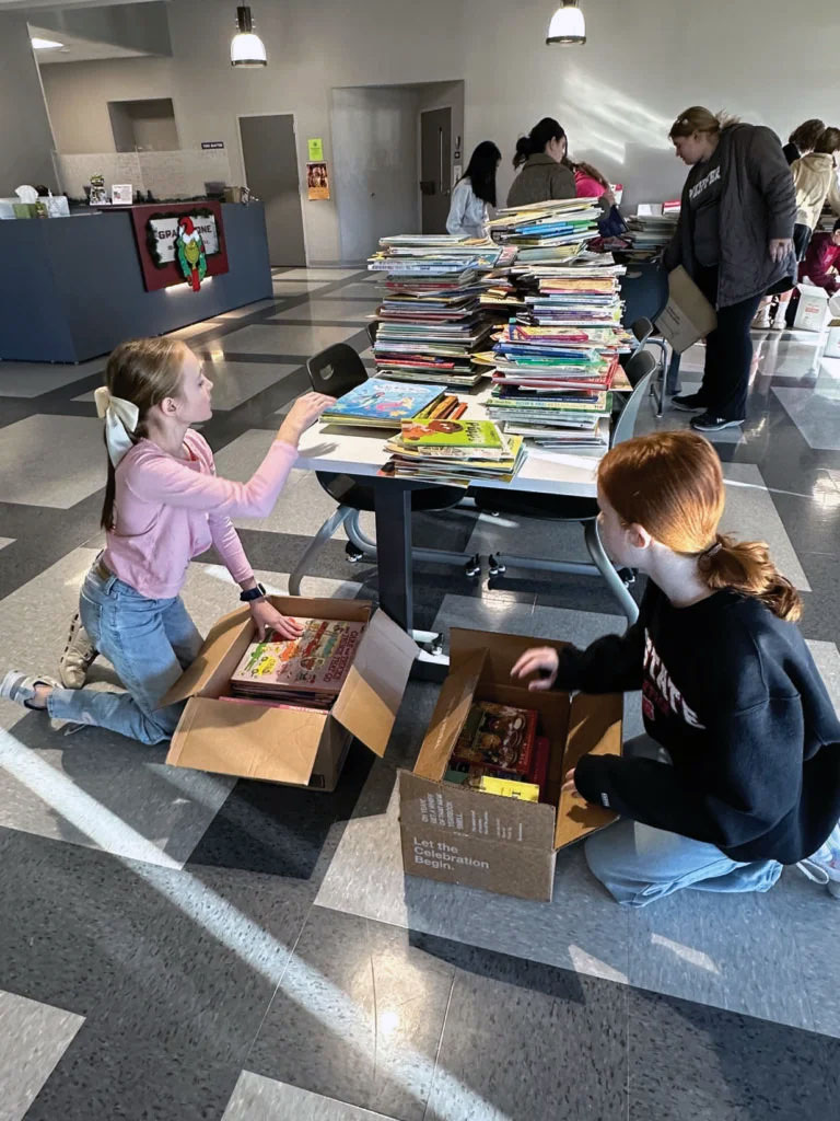 Gray Stone sixth graders Dempsey Rowland, left, and Mallory Johnson sort items in the book drive for Western North Carolina students.